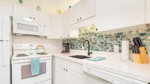 A kitchen with white cabinets, a microwave, a stove, a sink, and a dishwasher. - "Da Koa Bar" Paradise at Turtle Bay -Trade Winds, Beaches, Sunshine Rain, Resort (Kahuku)