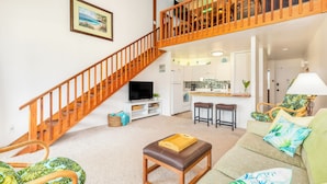 A spacious living area with a wooden staircase, a kitchen, and a dining area. - "Da Koa Bar" Paradise at Turtle Bay -Trade Winds, Beaches, Sunshine Rain, Resort (Kahuku)