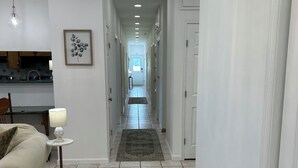 A hallway with a kitchen at the end, a rug, and a lamp.