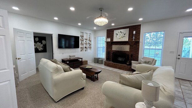A living room with a fireplace, sofas, a TV, and a ceiling light.
