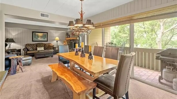 A dining area with a wooden table, benches, and chairs. There is a chandelier above the table. - Cozy Condo at Seven Springs
 (Champion)