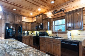 Kitchen features stainless steel appliances, wooden cabinetry, and granite countertops.