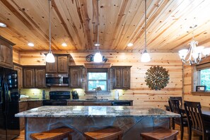 Enjoy cooking in this well-equipped kitchen with a large island, modern appliances, and a chandelier.