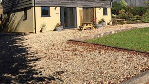 A single-story building with a sloped roof, a front door, and a small porch area. - Cosy country cottage for couples (BRIDPORT)