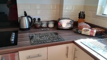 A kitchen with a kettle, toaster, and various jars on the counter.