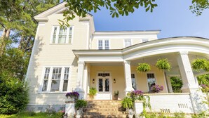 A two-story house with a front porch, steps leading to the entrance, and potted plants. - Luxurious Family Escape with Small Town Charm (Montezuma)
