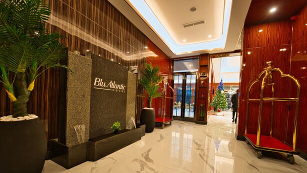 Un vestíbulo de hotel con piso de mármol pulido, una recepción y un árbol de Navidad.