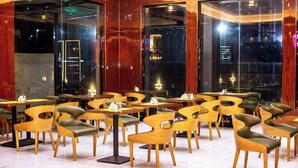 Un interior de restaurante moderno con mesas y sillas de madera, ventanas amplias y suelo de mármol.