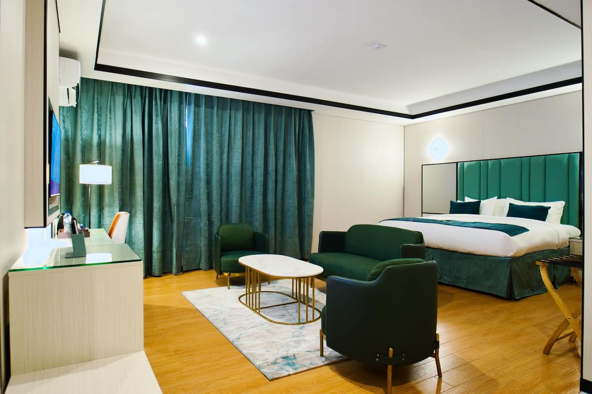A hotel room with a bed, a desk, a chair, a small table, and a couch.