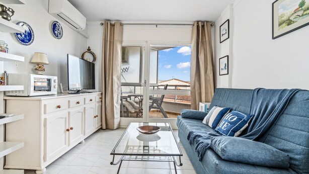 A modern living room with a sofa, a glass coffee table, a TV, and a balcony with a view. - WELCS APARTAMENTO 226 EMP frente al Canal (Empuriabrava)