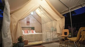 Ein Zeltraum mit Bett, Stuhl und kleinem Tisch.