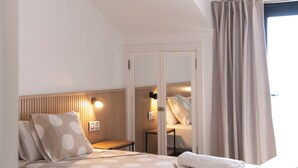 A hotel room with a bed, a nightstand, a mirror, and a window with curtains. - Breathtaking sea view, only 100 m to the sea and the beach, heated pool, wifi (Playa de la Américas)