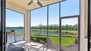 Un balcon avec vue sur un lac, une table et un canapé.