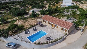 A villa with a swimming pool, outdoor seating, and a view of the sea and mountains. - Villa Nika (Novalja)