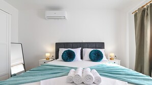 A hotel room with a bed, two bedside lamps, a nightstand, a rolled white towel, and a teal blanket. - Villa Nika (Novalja)