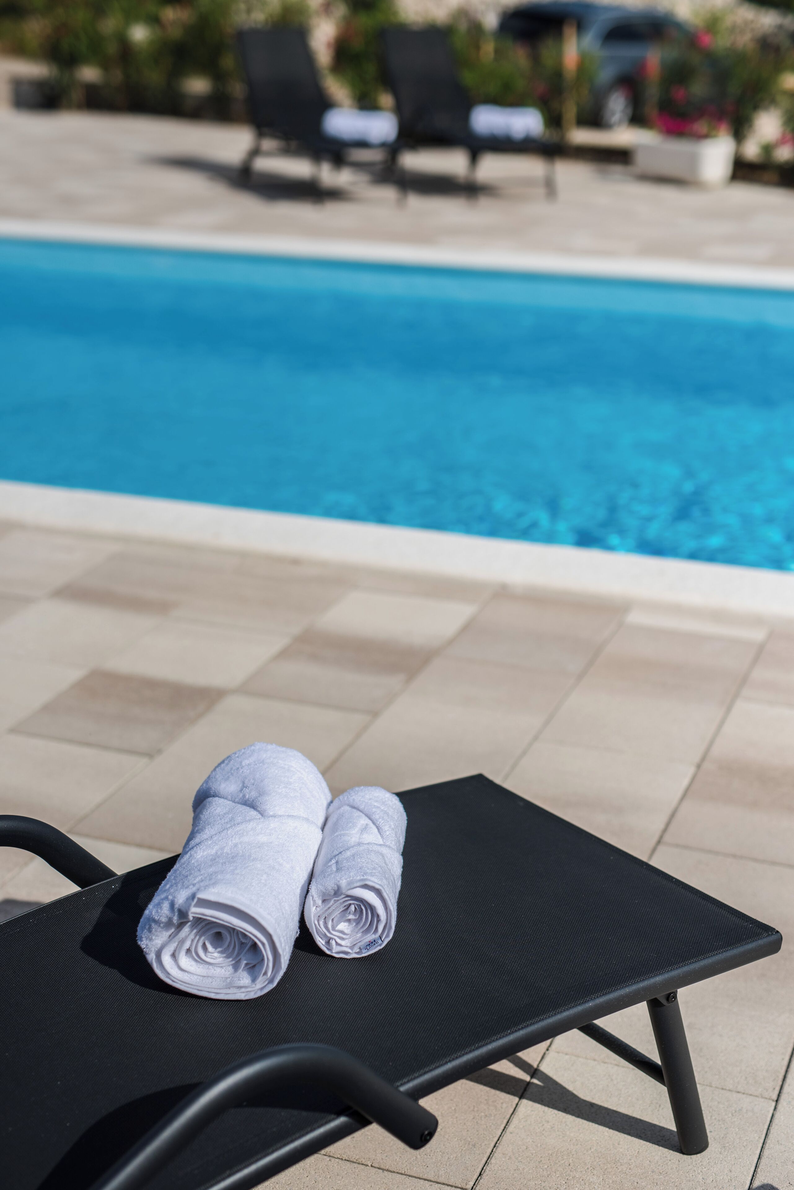 Una poltrona da relax a bordo piscina, con un asciugamano e una piscina sullo sfondo.