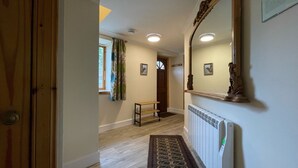 A hallway with a wooden door, a bench, a radiator, and a mirror on the wall.