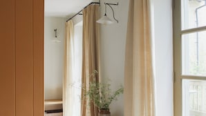 Ein Flur mit einer Holzbank, einem Blumentopf und einem großen Fenster mit Vorhängen.