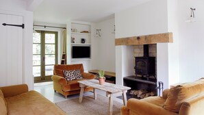 Ein Wohnzimmer mit einer Couch, einem Couchtisch, einem Kamin und einem Fernseher.
