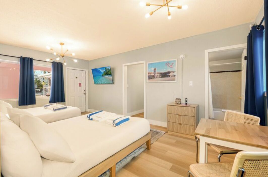 Een hotelkamer met twee bedden, een houten eettafel en een klein kastje.
