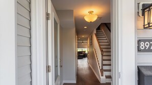Un couloir avec un escalier en bois, une porte et une boîte aux lettres portant le numéro 897.