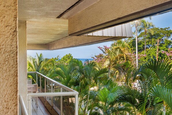A balcony with a view of lush greenery and a clear sky.