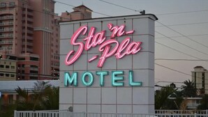 A neon sign for the St. Pete Motel with a modern building in the background. - 3 min to beach ~ pool ~ free parking ~ (Clearwater)