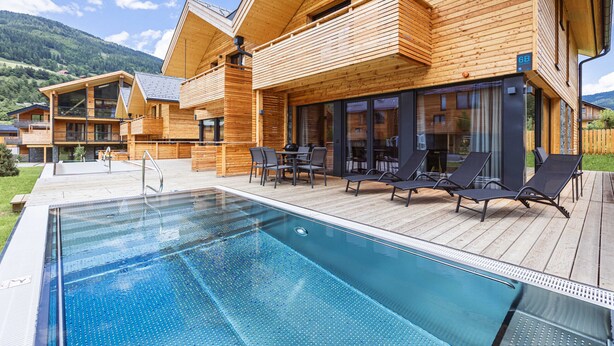Une cabane en bois avec une piscine, un espace salon extérieur et une vue sur les montagnes.