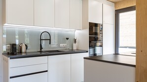 Une cuisine moderne avec des meubles blancs, un plan de travail noir et des appareils en acier inoxydable.