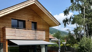 Ein modernes Haus mit Swimmingpool, Holzterrasse und überdachter Außenlounge.