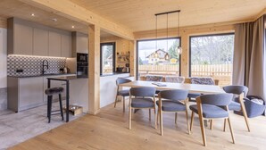 Eine moderne Küche mit einer großen Kochinsel, Holzboden und einem Essbereich mit Tisch und Stühlen.