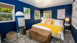 A bedroom with a bed, bedside lamps, a window with a view, and a wall with artwork.