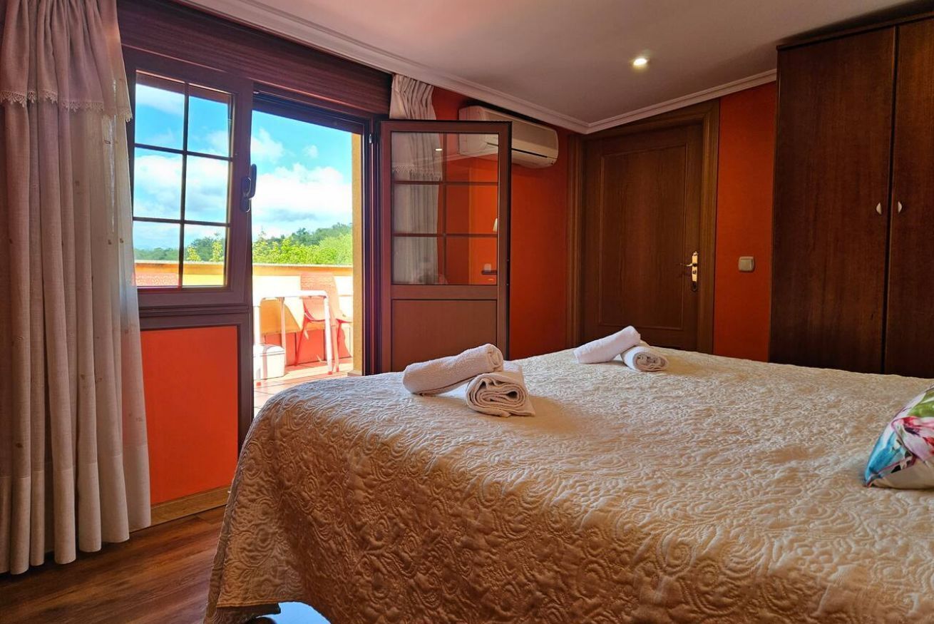 Une chambre d’hôtel avec un grand lit, une porte-fenêtre coulissante donnant sur un balcon et une armoire.