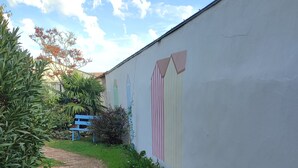 A paved pathway leading to a building with a wall featuring a colorful mural.