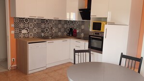 A kitchen with white cabinets, a black and white patterned backsplash, a microwave, and a stove.