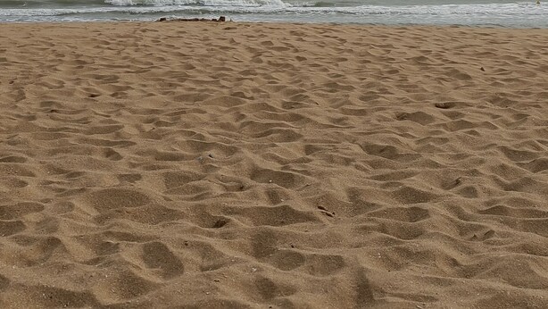 A sandy beach with footprints leading to the water.