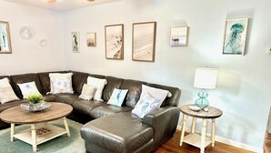 A modern living room with a sectional sofa, a round coffee table, a side table with a lamp, and framed artwork on the walls.