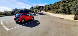 A parking lot with a red car parked in a marked space. - Golf & Sea Residence Is Molas - Sea view Suite (Pula)