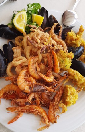 A seafood platter with shrimp, mussels, and squid rings, accompanied by lemon slices and a side salad. - Golf & Sea Residence Is Molas - Sea view Suite (Pula)
