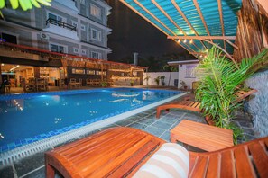 An outdoor swimming pool with wooden loungers and a bar area. - Majheri Resort and Spa (Pokhara)