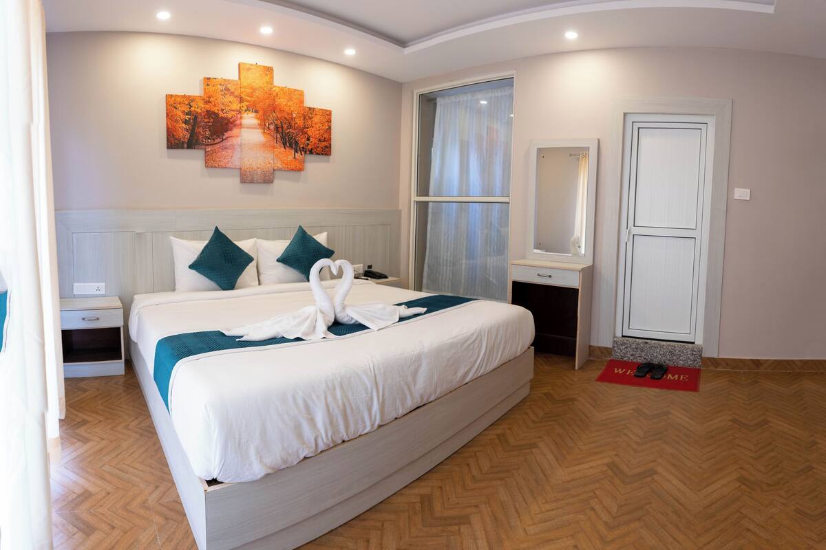 Ein geräumiges Schlafzimmer mit einem großen Bett, einem Nachttisch, einem Spiegel und einer Tür.