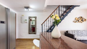 A modern kitchen with a stainless steel refrigerator, a wooden floor, a marble countertop, and a vase with yellow flowers. - Exclusive Penthouse close to the beach, heated pool, aircondition, dishwasher (Playa de la Américas)