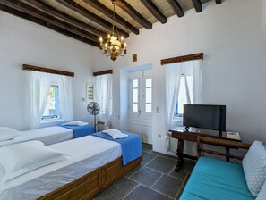 Traditional room with two single beds, wooden nightstand, and television.