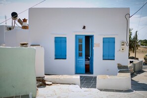 Stylish building with a blue door and matching shutters, featuring a small balcony and a satellite dish.