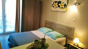 A hotel room with a bed, a table with a tray of food, a lamp, and a painting on the wall. - Studio Plein sud Avec Terrasse vue Centre Village (Saint-Jean-Saint-Nicolas)