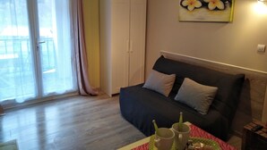 A bedroom with a bed, a wardrobe, a painting, and a table with cups and a plate. - Studio Plein sud Avec Terrasse vue Centre Village (Saint-Jean-Saint-Nicolas)