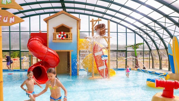 An indoor water park with slides, a playhouse, and a large water feature.