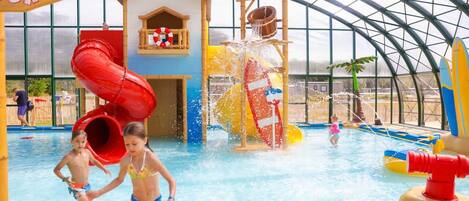 An indoor water park with slides, a playhouse, and a pool area.