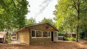 A log cabin with a front porch, large windows, and a door.