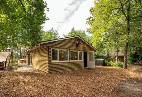 A log cabin with a front porch, large windows, and a door.